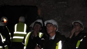 A group of people wearing hardhats in a dark, stone castle