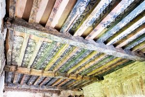 Ceiling beams in a clearly old property, covered with brightly painted decoration.