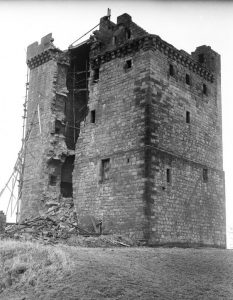 A black and white photo of a medieval tower (Clackmannan Tower) with a large area of collapsed stone in one wall.