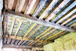 A wooden ceiling decorated with black markings and patterns