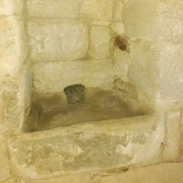 A clearly old, stone built sink sunk into a wall.