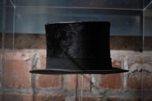 A felted top hat inside a display case