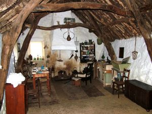 A cottage with a low, wooden ceiling and lots of historic objects inside