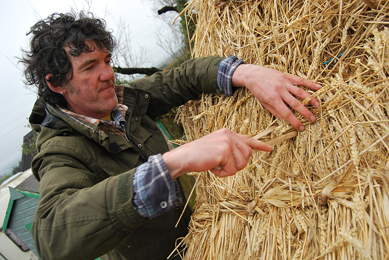 A thatcher demonstrates how to thatch a roof using hazel scobs