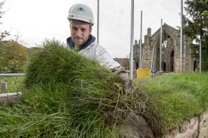 A stonemason covering the brewery yard wall at Melrose Abbey with turf