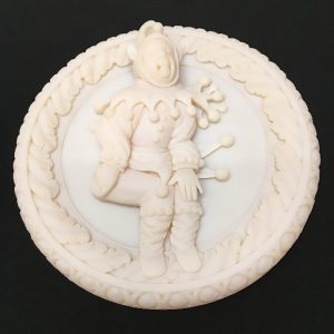 A white, round 3D print featuring a jester design