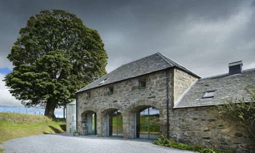 Traditional building Burmieston Steading with glass-fronted archways and a tree in the background
