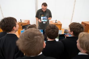 Chris showing schoolchildren an ipad and photos of traditional buildings