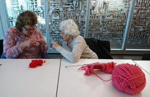 Two people knitting with pink wool