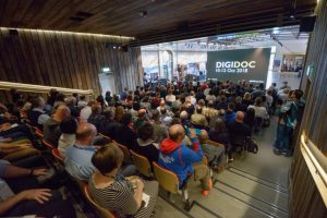 People sitting inside the Engine Shed auditorium with a DigiDoc slide on a screen