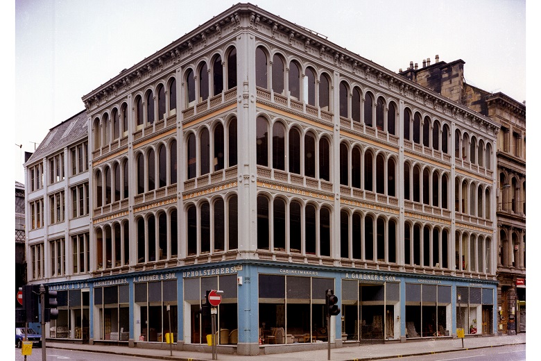 A four story building with large windows, glad in a cream coloured iron