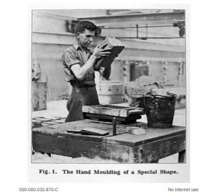 A person moulding a large brick by hand in a factory