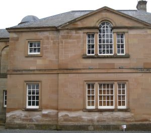 A slarge stone building. The bottom of the building has white markings on the stone from salt.