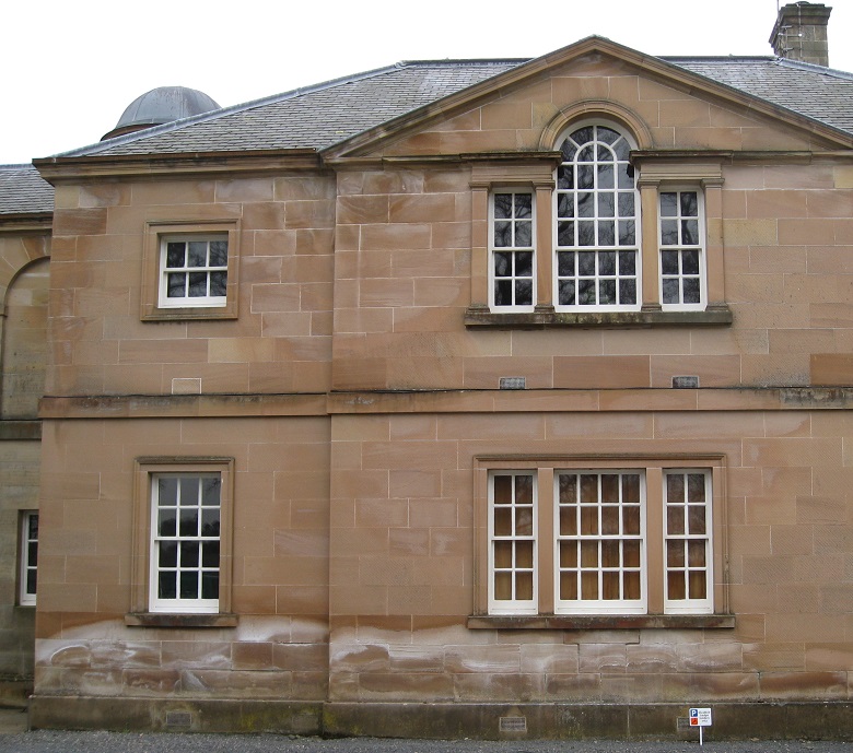 A large stone building with white marks from salt running along the bottom of the stone