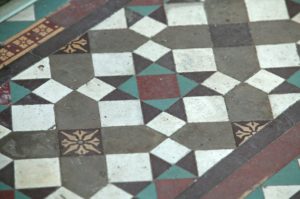 A mosaic floor made up of red, brown, green and yellow tiles