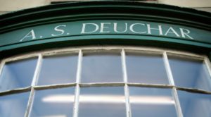 A curved shopfront window with the words A.S Deuchar above the window