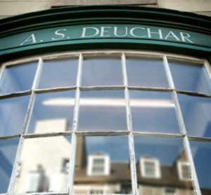 A curved shopfront window with the words A.S Deuchar above the window