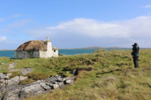 Someone taking a photo of a thatched cottage by the sea