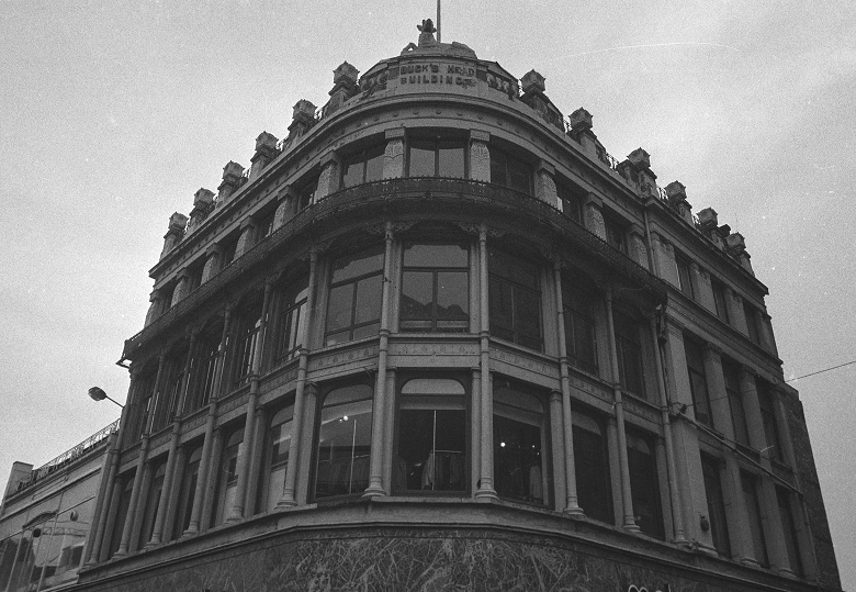 A stone building with large windows, ironwork features and columns