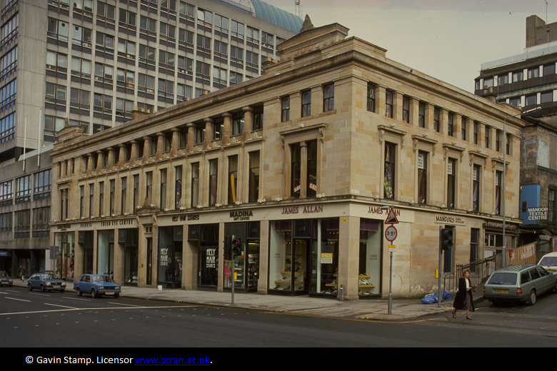 A large sandstone building with shops on the bottom floor