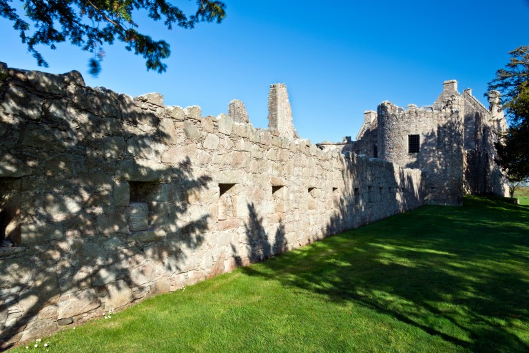 A long, historic stone wall with many rectangular coves cut into the wall, storing baskets with bees.