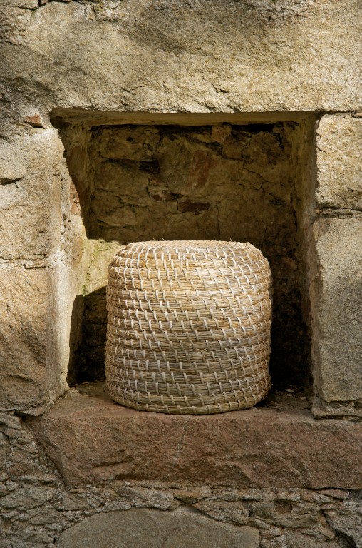 A straw basket set inside a cove in a stone wall.