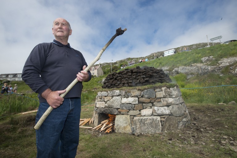 A person standing in front of a small stone lime kiln