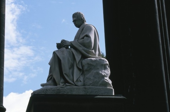 A marble statue of a person sitting with their dog