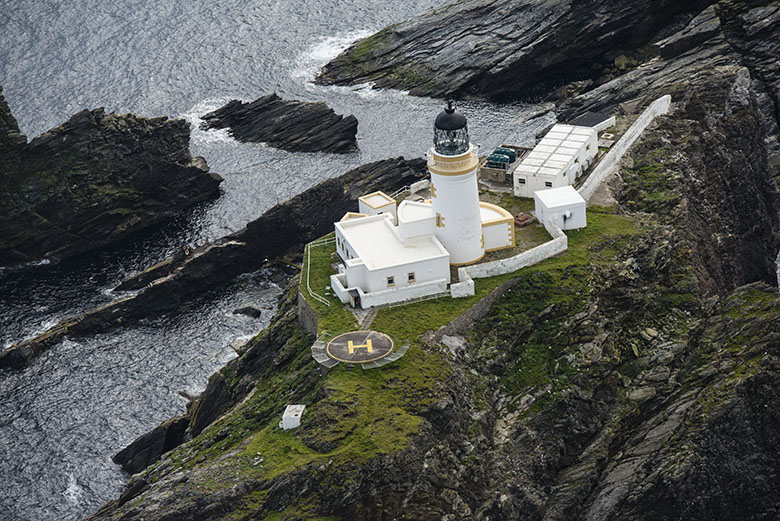 A lighthouse and outbuildings on a small strip of rocky land