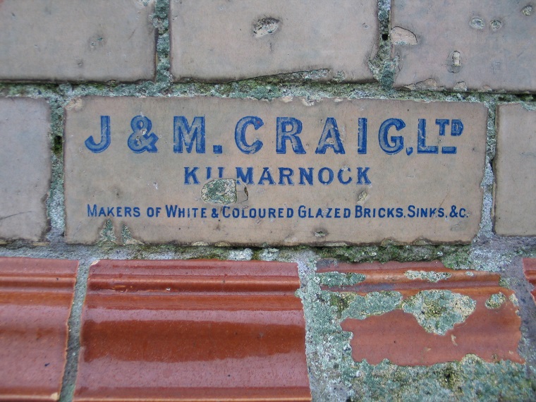 A glazed brick in a wall, decorated with the name of the manufacturers 