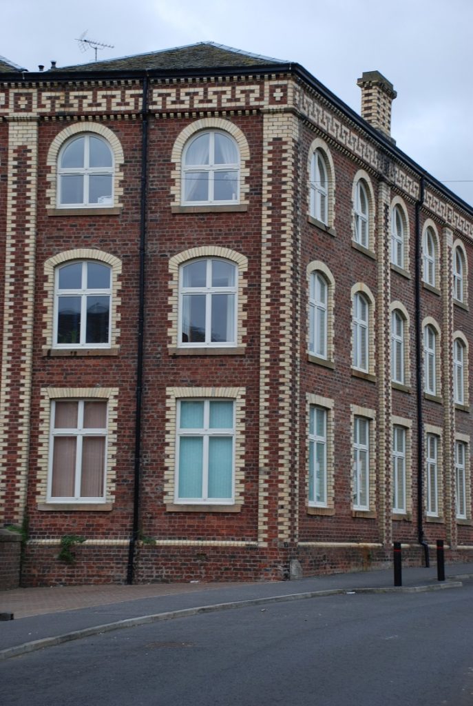 A dark red brick building with cream bricks surrounding the windows