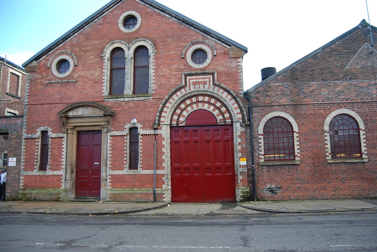 A red brick building with lighter bricks surrounding the doorways and windows