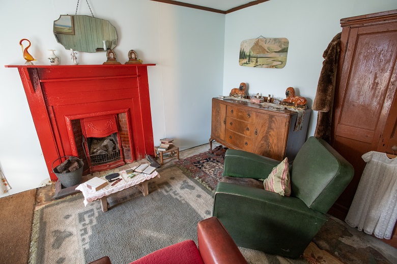 A cottage living room with a red iron fireplace and vintage furniture