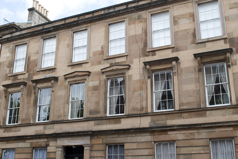 A row of stone tenement buildings with sash and case windows