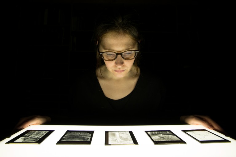 A person looking down at archive photos placed on a table