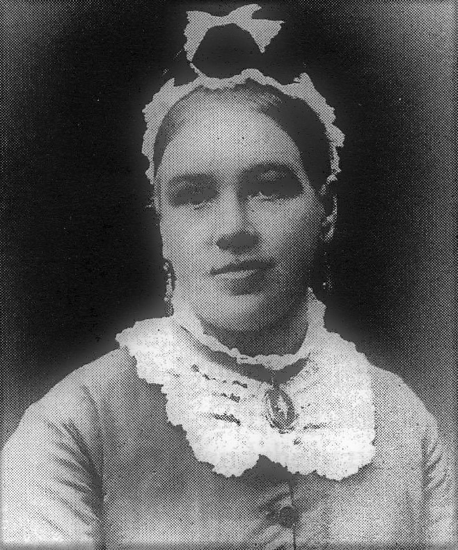 A woman wearing a ruffled collar and headband, smiling in a portrait photo