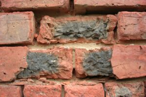 A close-up of a brick wall, with two central bricks having weathered away and crumbled in their place in the wall.