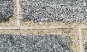 The weathered exterior of a historic building seen in closeup. The mortared stones are divided by brighter limewash giving a square grid shaped pattern.