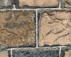 The weathered exterior of a historic building seen in closeup. The mortared stones are divided by brighter limewash giving a square grid shaped pattern.