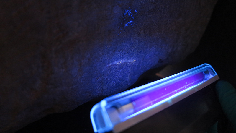 A UV light held up to the stone of destiny, emitting a purple light on the stone