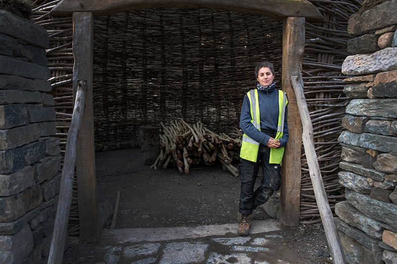 A person wearing a high vis vest, standing in the doorway of a traditionally constructed building