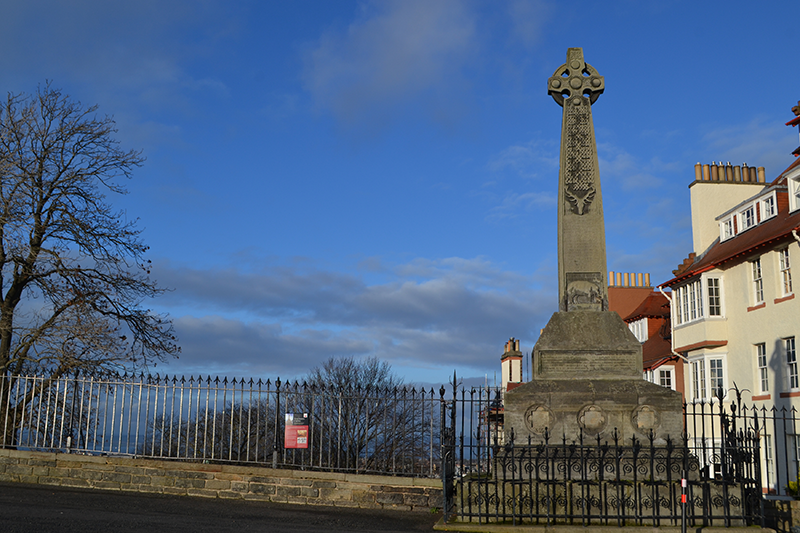 A large, stone monument. It is a cross, with patterns down the body of the cross.