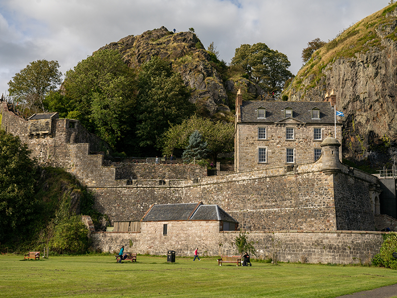 A complex of historic stone castle buildings in excellent condition, with slate roofs and sash and case windows. They are nestled within a rocky crag.