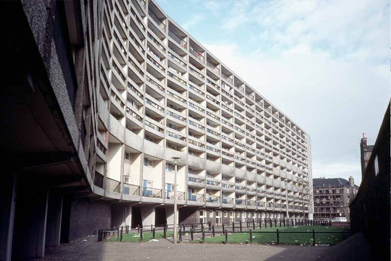A concrete, multi-storey building, which is long and is made up of many flats with balconies