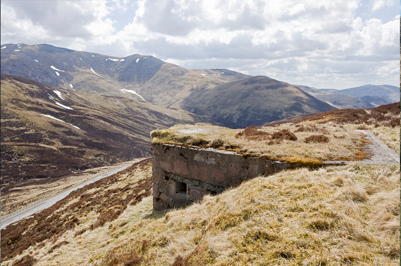 A small, rectangular concrete structure jutting out from a hillside in the rugged Scottish landscape