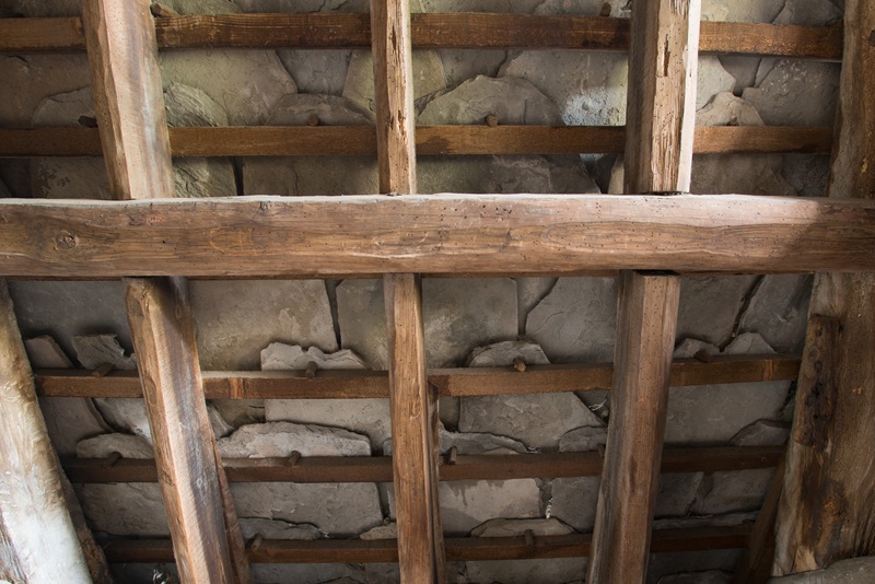 Wooden roof rafters and battens, supporting flagstones stacked overlapping each other