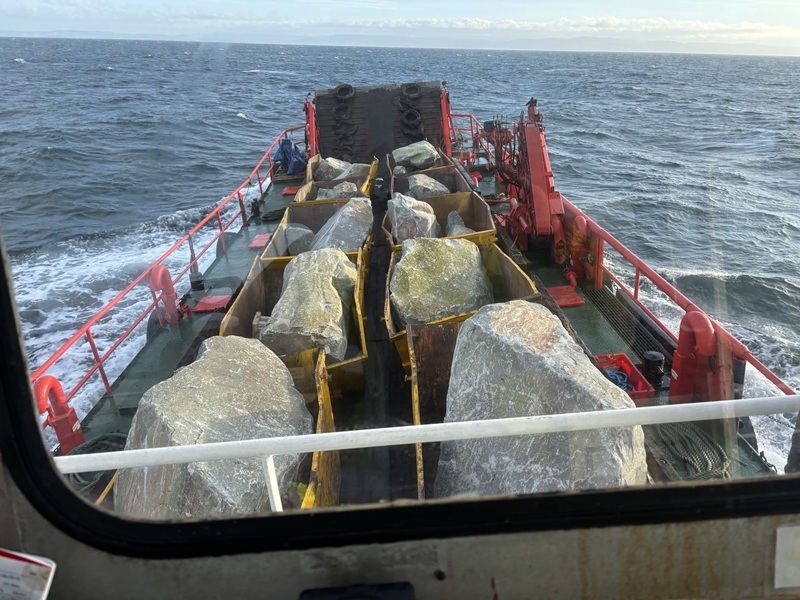 Large boulders being transported across the sea on a boat