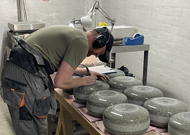 A person making curling stones on a table in a workshop