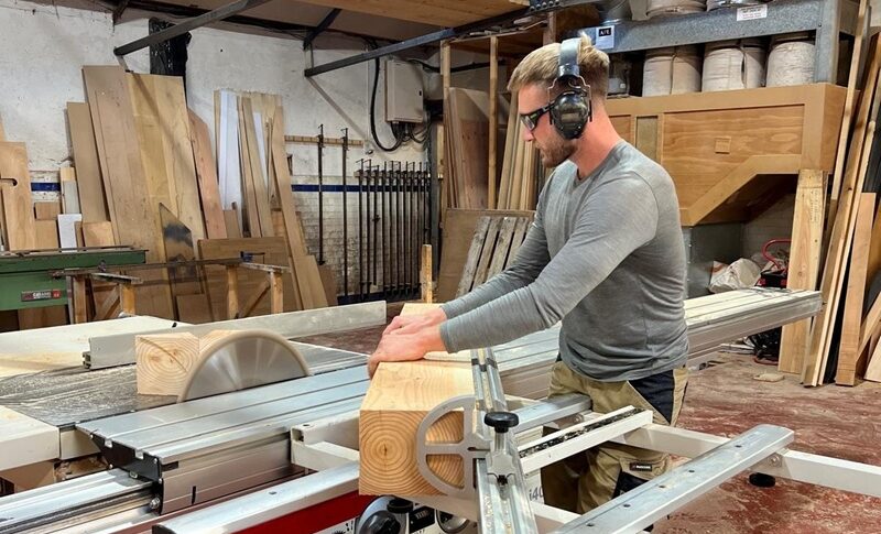A person working with a large block of wood in a workshop.