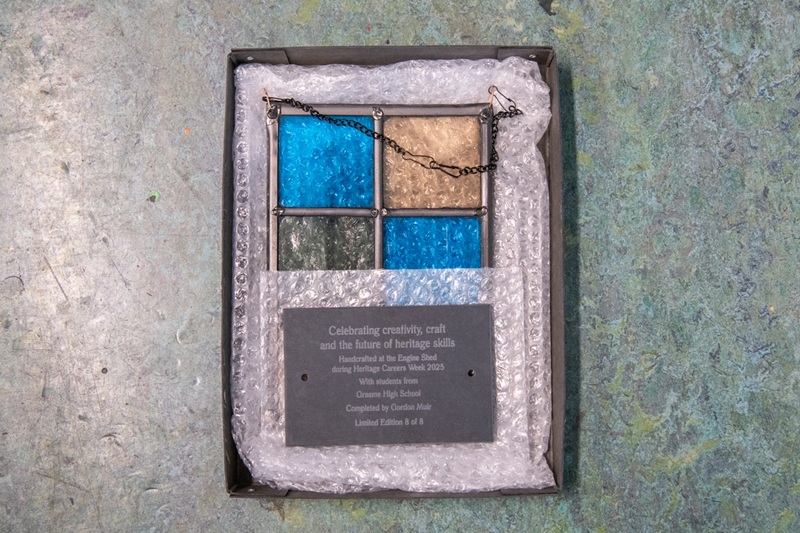 A panel made up of blue, green and orange stained glass panels fused together with lead